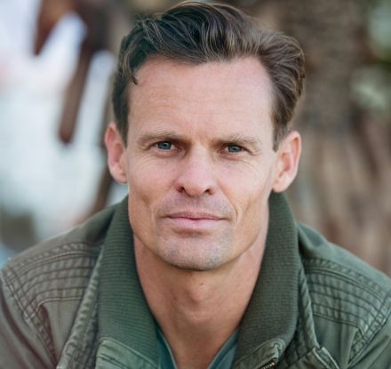 Close-up portrait of a man wearing a casual jacket outdoors.