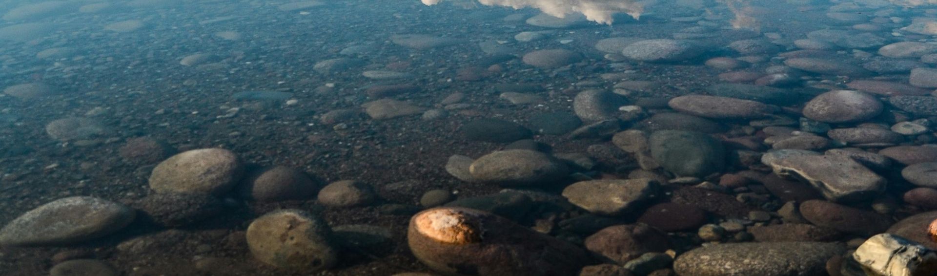 Tranquil lake reflecting mountains and sky, showcasing nature's beauty.